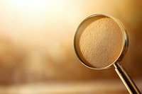 Magnifying glass on golden background with dramatic lighting and shallow depth of field creates mysterious investigative atmosphere for detective concepts.