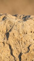 Weathered sandstone rock formation with natural cracks and erosion patterns in warm desert landscape for geology and nature backgrounds.