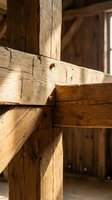 Rustic wooden beam construction detail showing traditional timber frame joinery with natural wood grain and weathered texture in historic building interior.