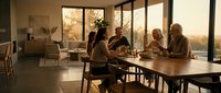 Diverse group of professionals collaborating at wooden table during golden hour meeting in modern office with large windows and natural light.