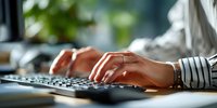 Professional woman hands typing on black keyboard at modern office desk with natural lighting and blurred green background for productivity concepts.
