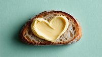 Heart-shaped butter melting on rustic artisan bread slice, breakfast comfort food concept for romantic morning meals and cozy dining experiences.