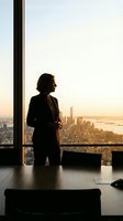 Professional businesswoman silhouette standing by office window overlooking city skyline at sunset, corporate success and leadership concept.