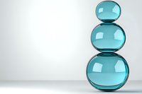 Stacked turquoise glass spheres creating balanced zen composition on light background. Minimalist decorative arrangement showcases transparency and reflection.
