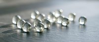 Clear glass marbles scattered on wooden surface with soft natural lighting creating reflections and transparency effects for creative projects.