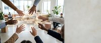 Diverse team of professionals stacking hands together in office meeting, showing unity, collaboration and teamwork commitment for corporate success and business goals.