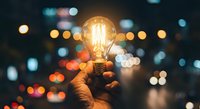 Hand holding glowing vintage light bulb against blurred city lights background at night. Innovation creativity inspiration concept for business solutions.