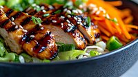 Grilled teriyaki chicken breast sliced and served on fresh salad with carrots, green onions and sesame seeds in dark bowl. Asian fusion cuisine.