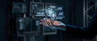 Businessman in dark suit holding glowing shield icon with trust, security, and protection text in digital interface environment for cybersecurity concepts.
