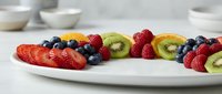 Fresh mixed berries and kiwi slices arranged on white plate for healthy breakfast, dessert presentation, or nutritious snacking options.