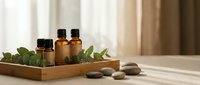 Essential oils in amber bottles with eucalyptus leaves and spa stones on wooden tray for aromatherapy wellness and natural skincare treatments.