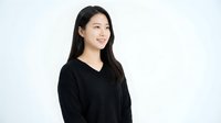 Young Asian woman in black v-neck sweater smiling confidently against white background, professional portrait for business and lifestyle content.