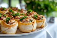 Freshly baked savory pinwheel pastries filled with ham and cheese, garnished with fresh parsley served on white plate. Close up view with soft background.