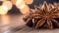 Star anise pods on wooden surface with soft golden bokeh lights in background creating warm atmospheric mood for culinary and seasonal designs.