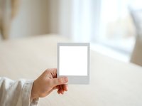 Hand holding blank instant film photo frame with white empty space for mockup or template design, suitable for branding, marketing materials, and creative projects.