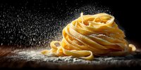 Fresh homemade pasta nest with flour dusting against dark background, dramatic food photography for restaurant menu or cooking blog.