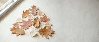 Autumn maple leaves scattered on white wooden floor near window creating warm seasonal home decor atmosphere for fall interior design projects.