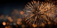 Spectacular golden fireworks exploding against night sky with blurred bokeh lights creating festive atmosphere for celebrations and holiday events.