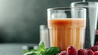 Fresh raspberry smoothie with mint leaves and ingredients on dark background, selective focus on glass of pink protein drink for healthy lifestyle.