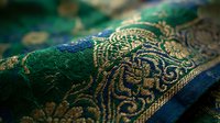 Luxurious green and gold brocade fabric with intricate paisley patterns and metallic thread embroidery for traditional clothing and textile design projects.