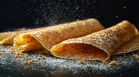 Golden crepes filled with orange jam dusted with powdered sugar on dark surface for breakfast dessert menu culinary photography food styling.