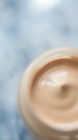Creamy beige cosmetic product swirl in jar against soft blue background, suitable for skincare, beauty, and wellness marketing materials.