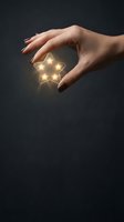 Female hand with manicured nails holding glowing star against dark background. Represents success, achievement, hope and aspirations for business and motivational concepts.
