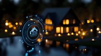 Futuristic smart home interface hologram with house icon glowing in blue against blurred background of residential houses with warm evening lights.
