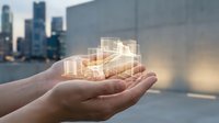 Hands holding glowing holographic building model with cityscape background, representing real estate development, property investment, and architectural planning for business concepts.