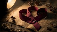 Burgundy satin ribbon curled into heart shape on rustic burlap with coffee beans and warm lighting for romantic Valentine's Day crafting projects.