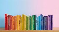 Colorful books arranged by rainbow spectrum on wooden shelf against gradient background for education, reading and library concepts.