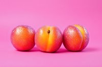 Fresh ripe peaches with water drops on bright pink background, minimal food composition for healthy eating and summer fruit concept.