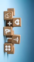 Wooden blocks with medical healthcare icons including stethoscope, cross, heart, bandage and caduceus symbol arranged on blue gradient background.