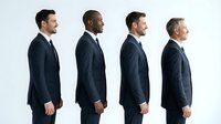 Four diverse professional businessmen in dark suits standing in profile line formation showing teamwork and corporate leadership succession.