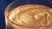 Creamy peanut butter swirl in glass jar on blue background, ready for cooking, baking, and food styling projects.