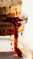 Stacked cork slices with deep red jam or preserve dripping down the sides against a white background, showcasing food preservation and artisanal ingredients.