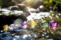 Colorful crystal gems scattered in water with sunlight creating magical sparkles and bokeh effects, mystical nature backdrop for spiritual and wellness designs.
