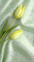 Pale yellow tulips on mint green polka dot fabric background create soft spring mood. Delicate floral composition with fresh blooms and green stems.