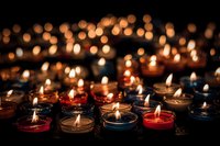 Colorful tea light candles burning in darkness creating warm atmospheric glow for meditation, prayer, or memorial ceremony.