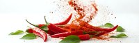 Red chili peppers with green leaves and paprika powder explosion on white background. Fresh hot spicy ingredients for cooking and seasoning isolated.