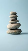 Balanced stack of smooth river stones arranged in zen tower formation on soft blue background representing mindfulness meditation and inner peace.