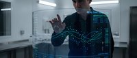 Young professional man interacting with futuristic holographic interface displaying data analytics in modern office environment for technology presentations.