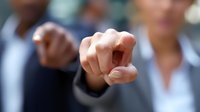Professional pointing finger at viewer in business setting, selective focus on hand gesture against blurred office background. Concept of leadership, recruitment.