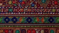Traditional ornate carpet with intricate geometric patterns and floral motifs in rich colors, featuring decorative borders for interior design projects.