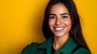 Young Hispanic woman with bright smile wearing green shirt against vibrant yellow background for lifestyle and portrait photography projects.