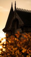 Gothic revival architecture silhouette against golden sunset sky with ornate spires and decorative trim creating dramatic atmospheric mood.