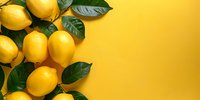 Fresh ripe lemons with green leaves arranged on vibrant yellow background, copy space. Natural citrus fruits layout perfect for healthy lifestyle and food marketing designs.