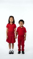 Two happy elementary school children in matching red uniforms holding hands on white background, ready for back to school designs.