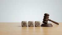 Wooden gavel with legal symbol blocks on desk representing justice system, law enforcement, court proceedings and judicial authority for legal concepts.