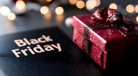 Red gift box with glitter ribbon on dark background with Black Friday text and blurred bokeh lights creating festive shopping atmosphere for seasonal sale promotion.